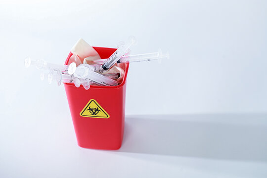 Hazardous contaminated medical waste bin filled with syringe plastic sharp container evoking urgent concern for safety