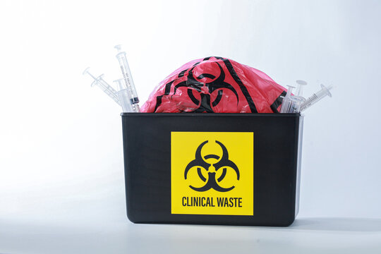 Hazardous clinical waste container filled with syringe and red biohazard bag evokes tense serious mood for safety medical disposal