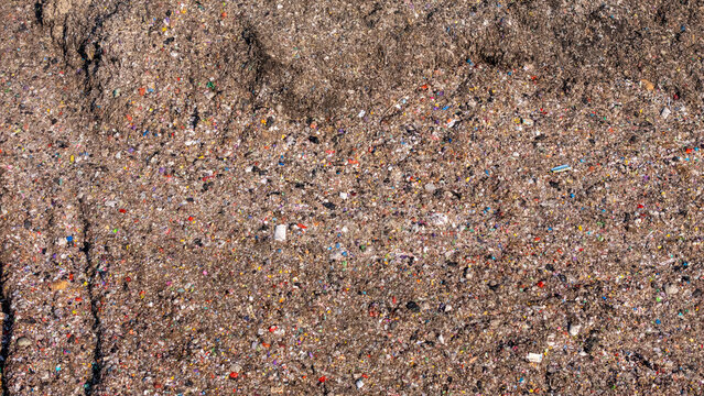 Aerial view of a large landfill site filled with piles of mixed waste, plastic debris, and discarded materials in Klaten, Central Java, Indonesia.