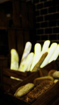 Warm light illuminates an assortment of bread placed in wooden baskets, filling the air with a delightful aroma in a bustling bakery during a cheerful morning.