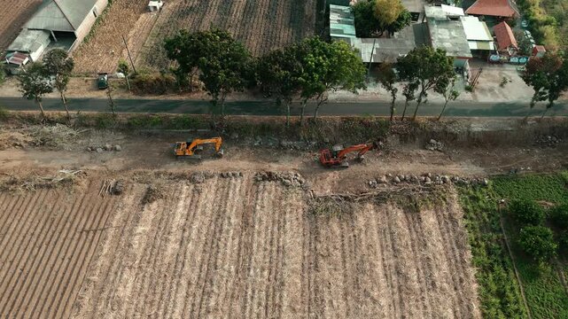 Drone footage showing an aerial view of agricultural fields, including harvested sugarcane and pomelo orange orchards, with heavy machinery parked near a rural road.