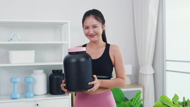 Fit Asian woman recording healthy diet and sports nutrition vlog in home kitchen. Active female content creator sharing organic food preparation and wellness supplement advice for vitality.
