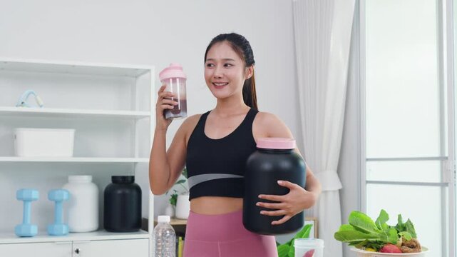 Fit Asian woman recording healthy diet and sports nutrition vlog in home kitchen. Active female content creator sharing organic food preparation and wellness supplement advice for vitality.