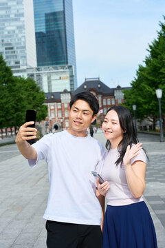 Young Japanese Man and Woman Taking Selfie Together on City Street