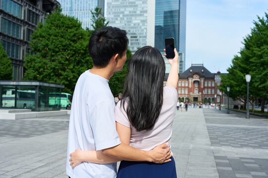 Young Japanese Man and Woman Taking Selfie Together on City Street