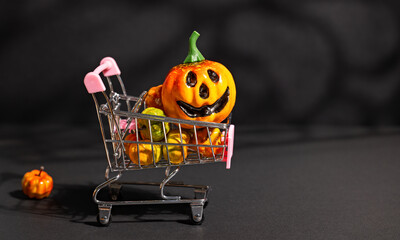 Jack-o-lantern in miniature shopping cart with small pumpkins on black background for Halloween retail sale or ecommerce promotion © Svetlana Kolpakova