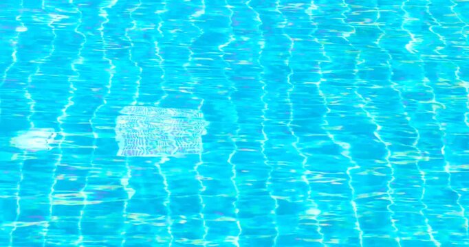 clear blue swimming pool water with shimmering reflections and tiled pattern, gentle moving ripples, abstract summer background ideal for travel, leisure, relaxation, wellness, refreshing, luxury pool