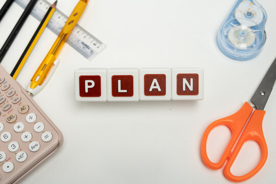 Business organization and administration concept featuring letter blocks spelling &ldquo;PLAN&rdquo; on a clean office desk, surrounded by office stationaries. Symbolizing corporate mission, strategic planning, b