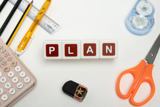 Business organization and administration concept featuring letter blocks spelling &ldquo;PLAN&rdquo; on a clean office desk, surrounded by office stationaries. Symbolizing corporate mission, strategic planning, b