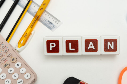 Business organization and administration concept featuring letter blocks spelling &ldquo;PLAN&rdquo; on a clean office desk, surrounded by office stationaries. Symbolizing corporate mission, strategic planning, b