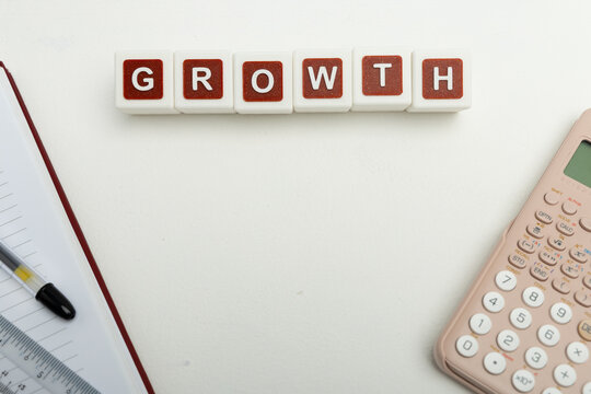 Business organization and administration concept featuring letter blocks spelling &ldquo;GROWTH&rdquo; on a clean office desk, surrounded by office stationaries.