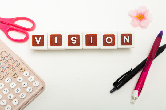 Business organization and administration concept featuring letter blocks spelling &ldquo;VISION&rdquo; on a clean office desk, surrounded by office stationaries.