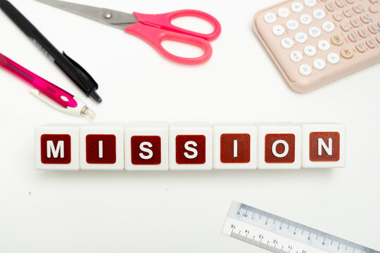 Business organization and administration concept featuring letter blocks spelling &ldquo;MISSION&rdquo; on a clean office desk, surrounded by office stationaries.