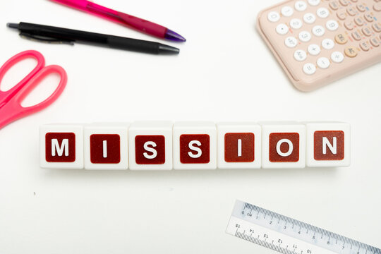 Business organization and administration concept featuring letter blocks spelling &ldquo;MISSION&rdquo; on a clean office desk, surrounded by office stationaries.