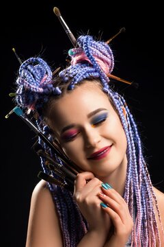 Creative makeup artist showcasing colorful hairstyle with brushes