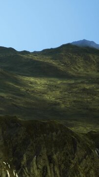 Vast green valleys stretch across a breathtaking landscape, while rugged mountains rise majestically in the background, bathed in the soft hues of sunset.