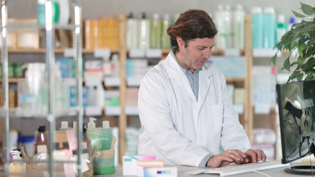  Adult man pharmacist working with computer in pharmacy