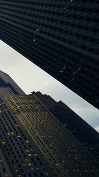 Tall skyscrapers stretch upward against a twilight sky, their windows glowing softly. The urban landscape reflects the blend of architecture and magical evening light.