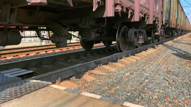 Heavy freight wagon bogie stands above rails beside crossing platform