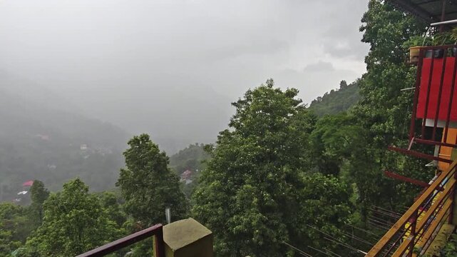 Scenic view of mist-covered green mountains and hills in Darjeeling, West Bengal, India, under an overcast sky. The footage captures the peaceful Himalayan landscape, winding mountain terrain