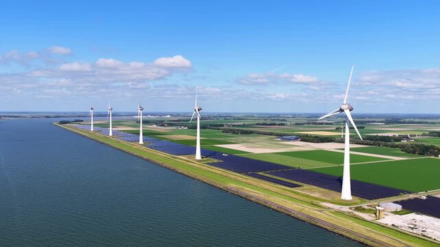 Aerial view of wind turbines and solar panels along the waterfront in the agricultural landscape of Rutten, Flevoland, Netherlands.