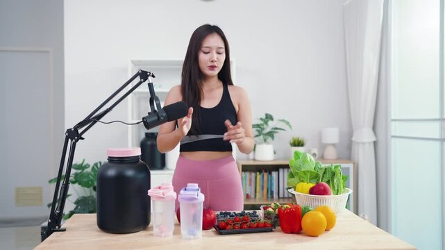 Asian fitness influencer recording healthy nutrition vlog with smartphone camera. Young female content creator talking about diet, fresh organic food and wellness lifestyle.