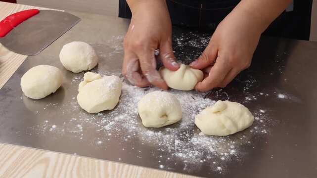 Hands of Chef Preparing Raw Dough Portions on Floured Metal Counter
