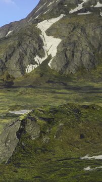 Majestic mountains rise in the background, adorned with patches of snow. Lush green slopes contrast beautifully with rugged rocks, creating a serene and breathtaking natural scene.