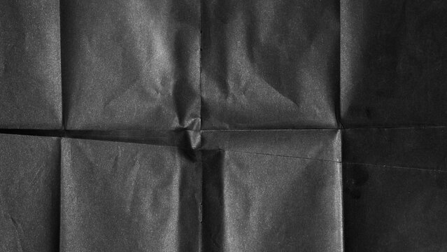 Black paper background with creases that separates paper symmetrically into four parts