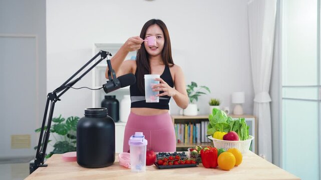 Asian fitness influencer recording healthy nutrition vlog with smartphone camera. Young female content creator talking about diet, fresh organic food and wellness lifestyle.