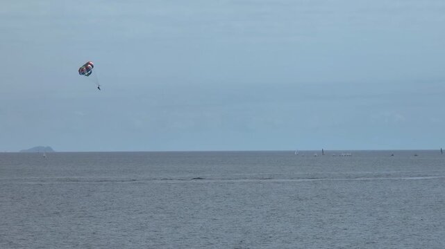 Telephoto view of a parasailer gliding over Pacific Ocean, sunny day in LA