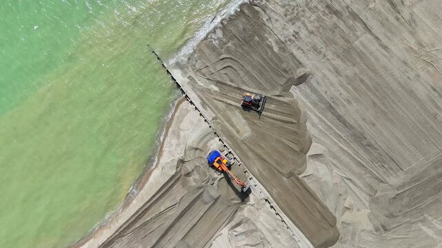 Newly installed timber groynes retain dredged shingle and strengthen the seafront against coastal erosion and flood risk. Aerial view. Hove, East Sussex, United Kingdom.