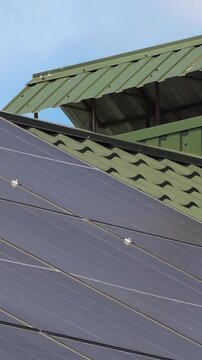 Solar panels installed on the roof of a city building. Concept of eco friendly and alternative power source - Vertical Video