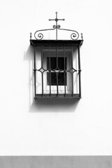 Obraz premium Window with wrought iron lattice on whitewashed facade in Seville city
