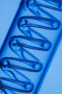 Abstract laboratory background coiled glass element in tube with blue lighting