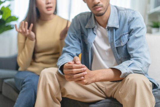 Family problem concept. Tension in relationship between married couple, husband and wife staying sitting separate after quarrel in the living room.