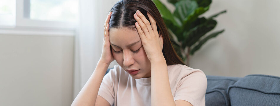 Asians female in stressed expression sitting on the sofa in the house.