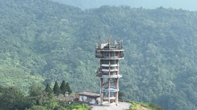 Aerial view of the communication tower at Puncak Pass Bogor surrounded by lush green mountains in Kecamatan Cisarua, Jawa Barat, Indonesia.