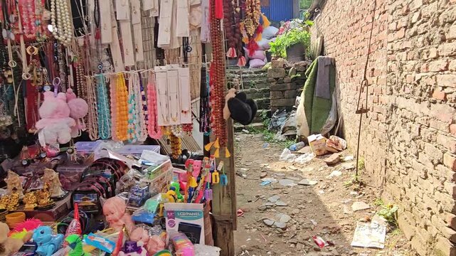 Colorful souvenir and religious items displayed at a market stall near Mankamana Temple in Nepal. The shop features prayer beads, malas, bracelets, decorative items, bells