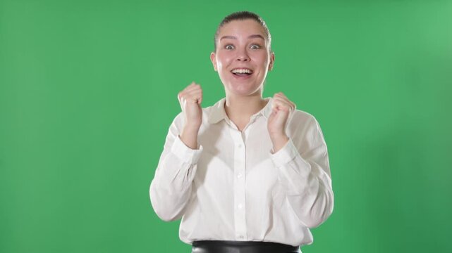 Joyful young woman in a white blouse and a black skirt stands against the background of chrome key. European woman stands against a green background and smiles emotionally