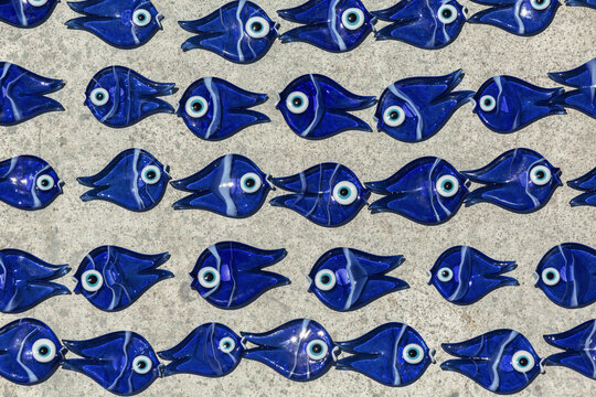 Blue evil eye glass fish souvenirs in neat rows, traditional mass-produced Turkish gift from Bodrum