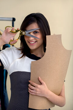Portrait of young fashion designer holding scissors and cardboard 