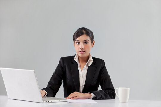 Portrait of news anchor with laptop and coffee against colored background 