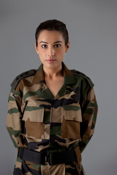 Portrait of young female soldier standing against colored background 