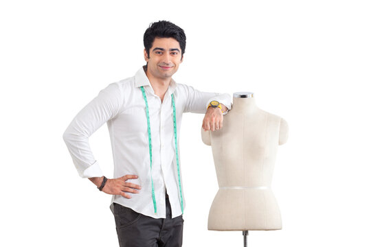 Young male fashion designer standing by mannequin over white background 