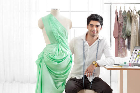 Portrait of smiling young male fashion designer with dressmaker's dummy 