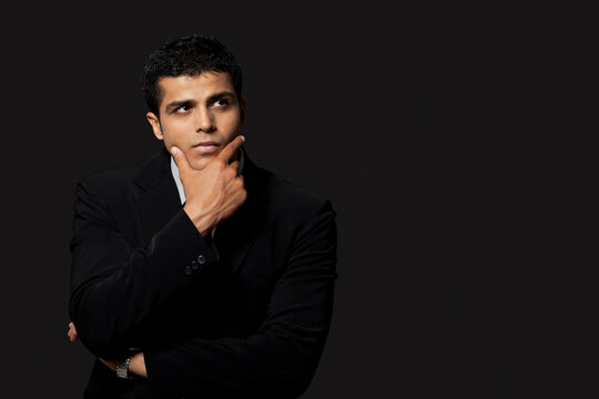 Thoughtful business man over black background 