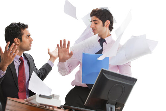 Frustrated businessman throwing papers on male executive 