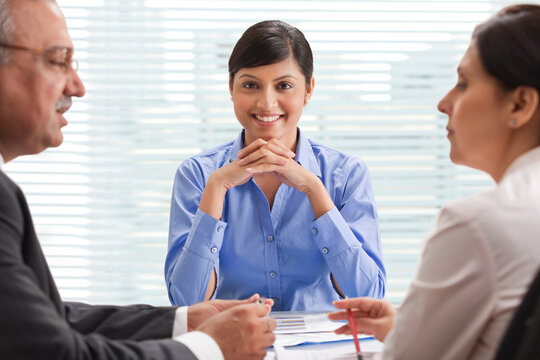 Smiling businesswoman with two executives discussing in office 
