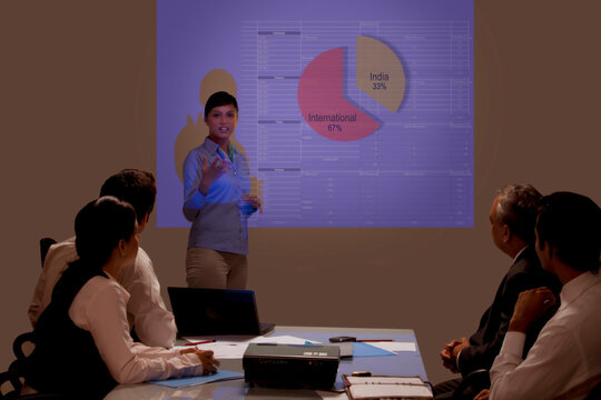 Businesswoman presenting on projection screen at seminar 